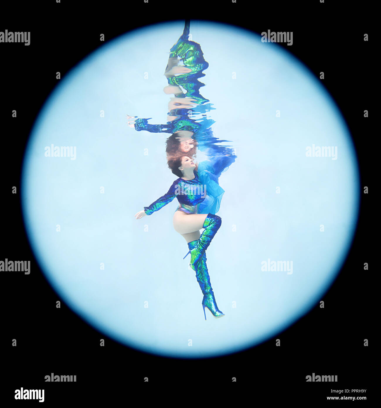 An underwater portrait of a woman wearing green and blue sequined stiletto boots and matching shirt. Stock Photo