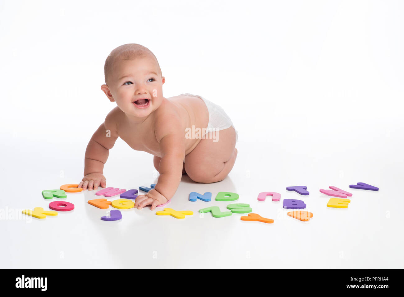 A laughing seven month old baby boy playing with foam alphabet toys