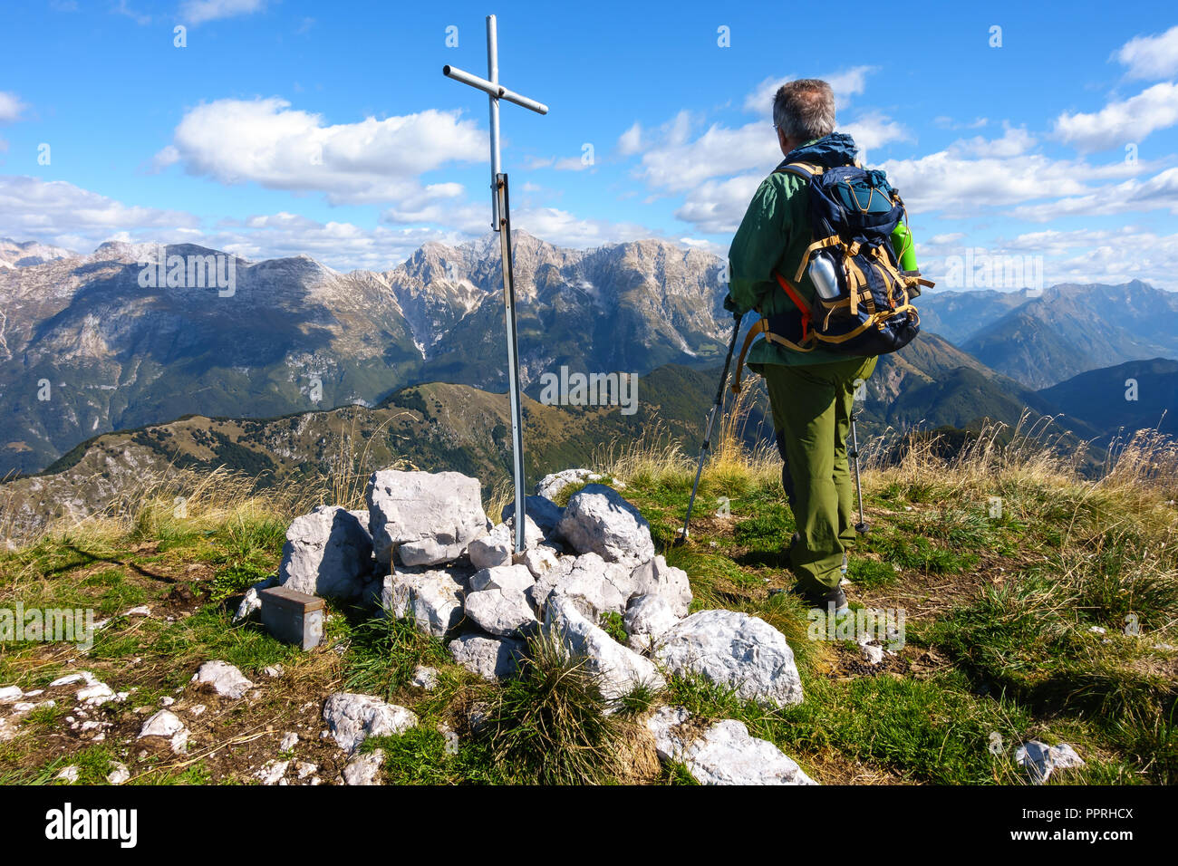 Man hiker, near the rood of top, on mountain top watching the mountain range. Stock Photo