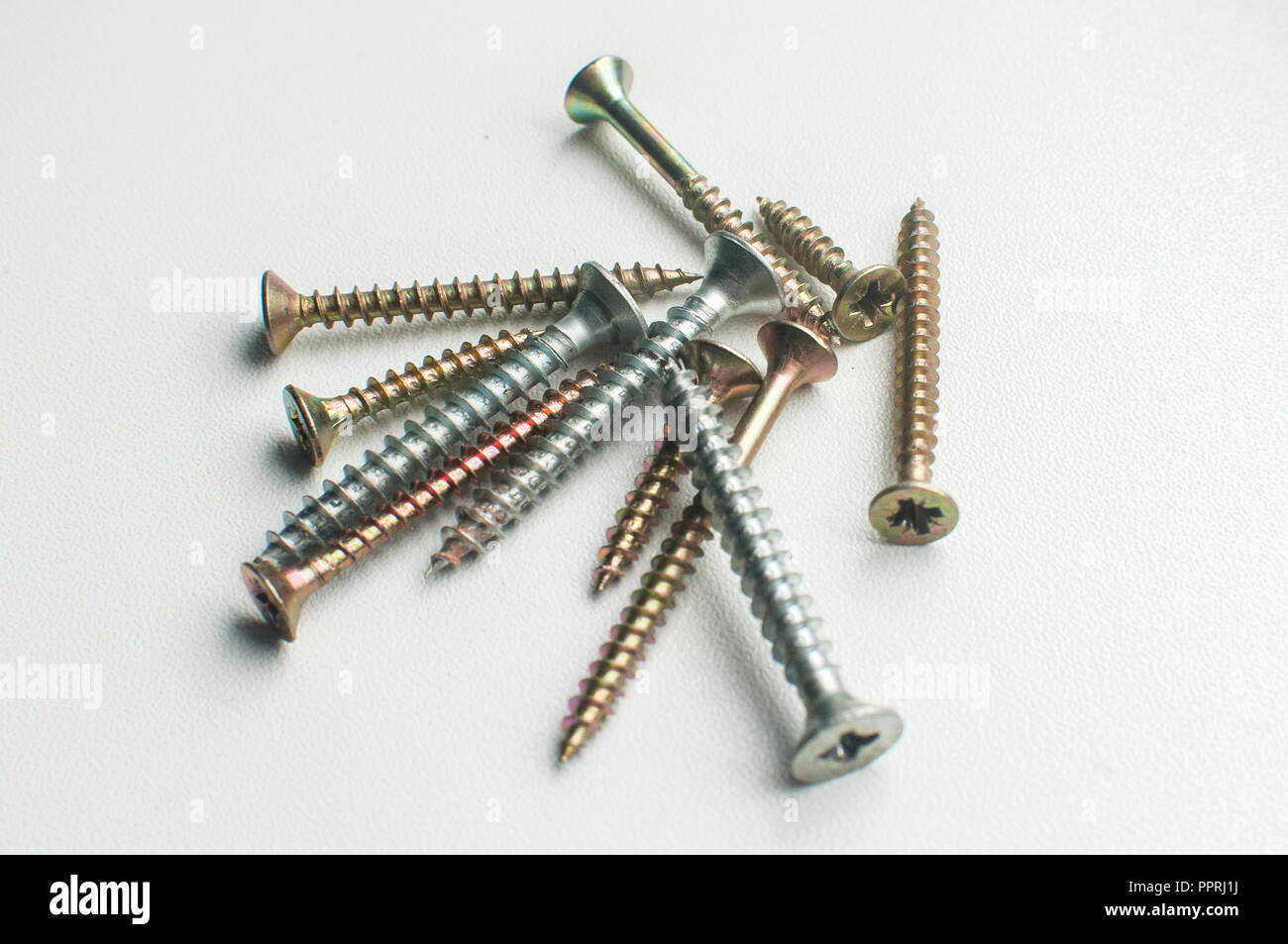 A pile of wood screws and screwdriver shaft head closeup on white background Stock Photo