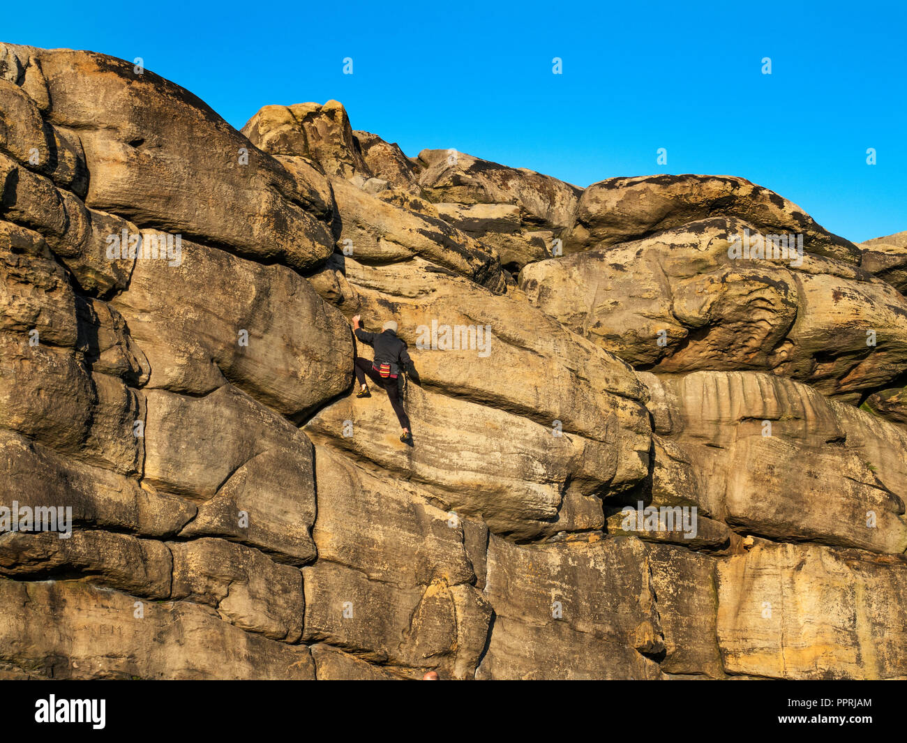 Rock climber at Almscliff Crag millstone grit outcrop near Harrogate North Yorkshire England Stock Photo