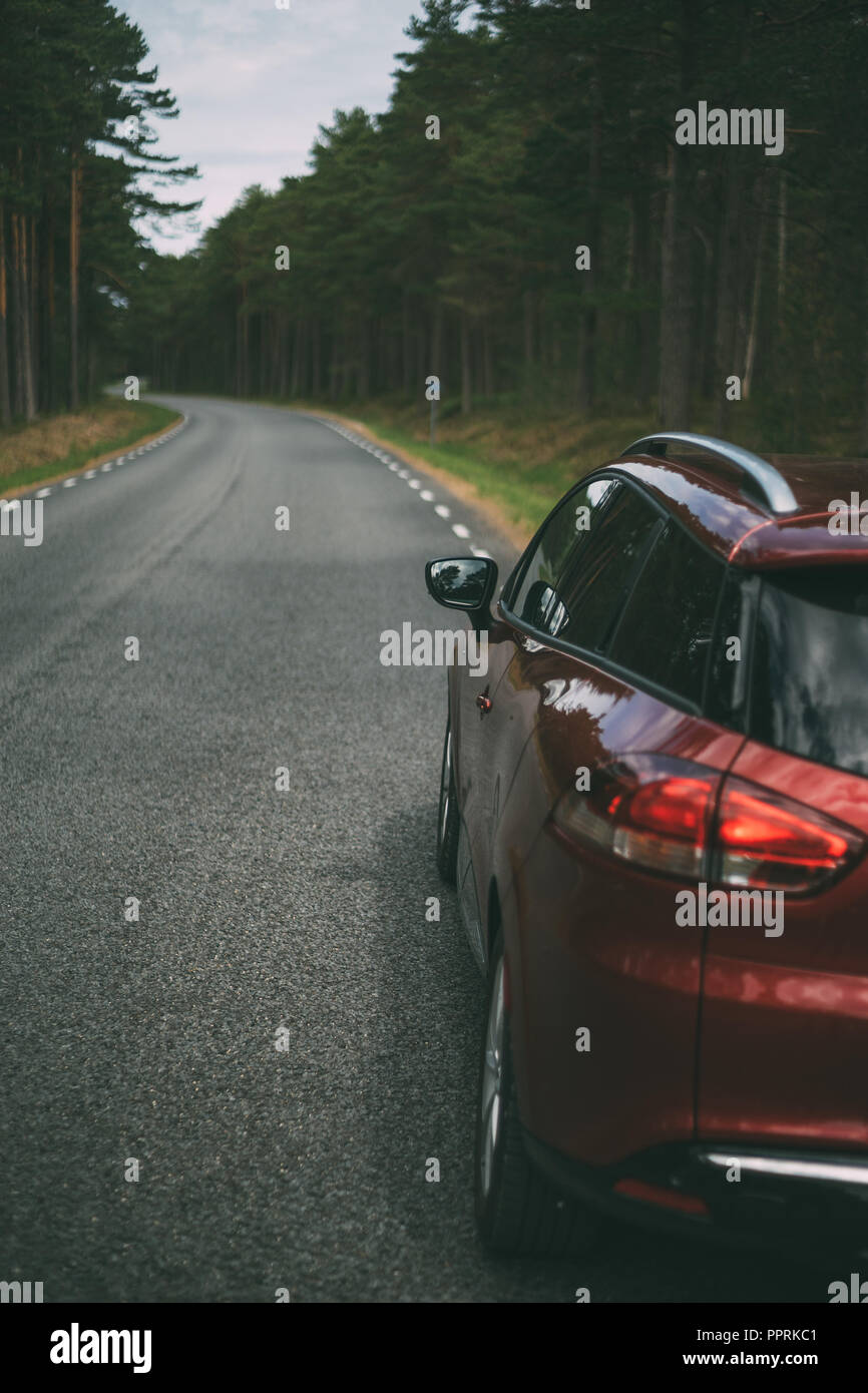Red car parked on winding road in forest area, vertical view Stock Photo