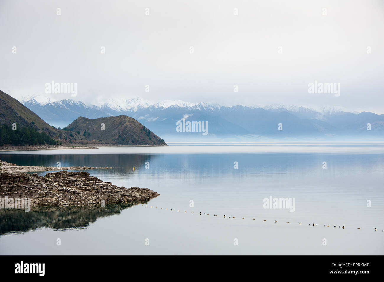 Peaceful scene on Lake Hawea, New Zealand. Soft grey tones, calm water and a mountain background. Stock Photo