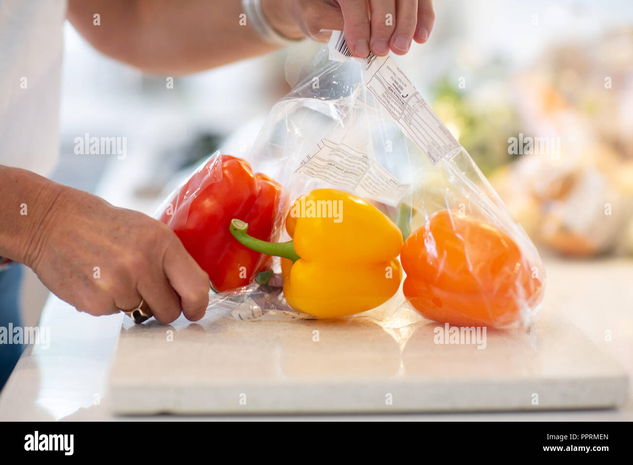 Unpacking plastic wrapped fruit and vegetables in the kitchen - Plastic packaging on fruit and vegetables in the UK Stock Photo