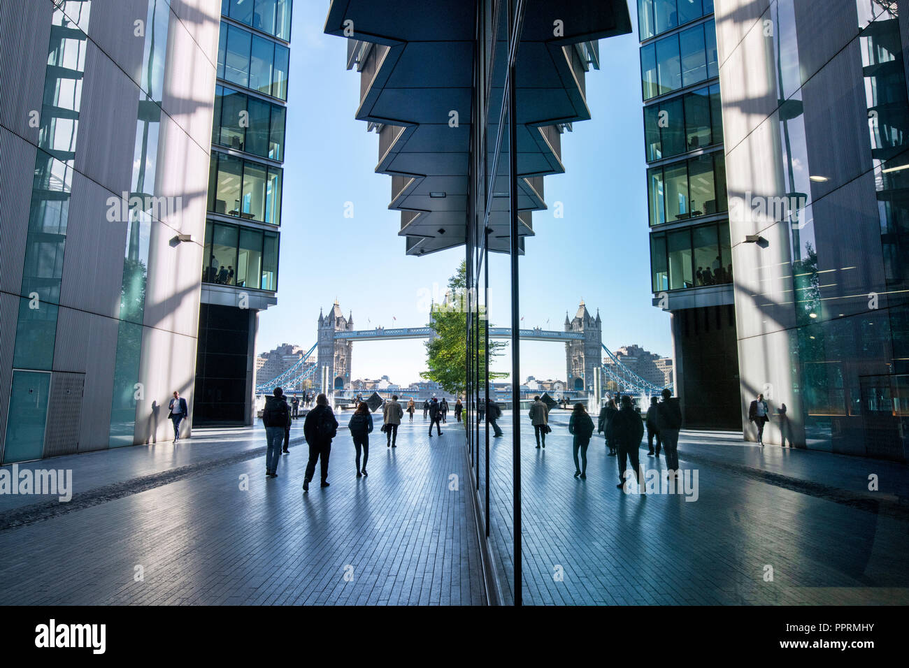 Tower bridge and office workers reflected in glass windows. More London Riverside.  London, England Stock Photo