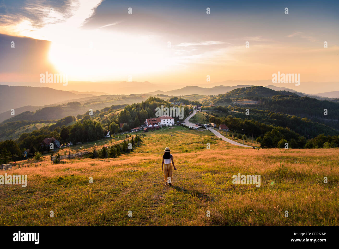 Woman walking down the hill with a view at sunset Stock Photo