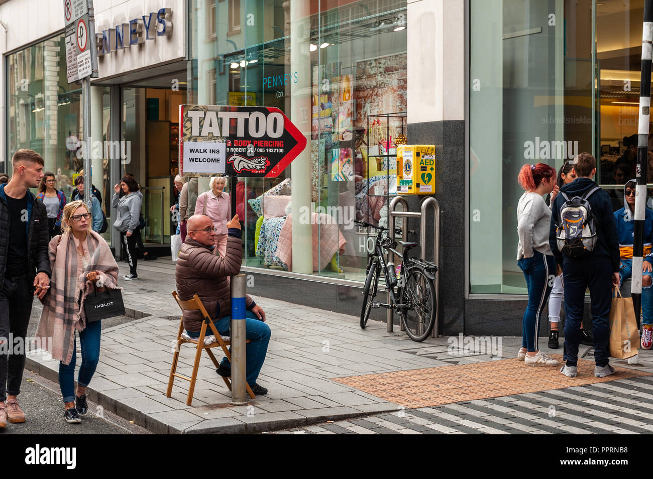 Man holding tattoo shop sign on Oliver Plunkett Street, Cork, Ireland. Stock Photo