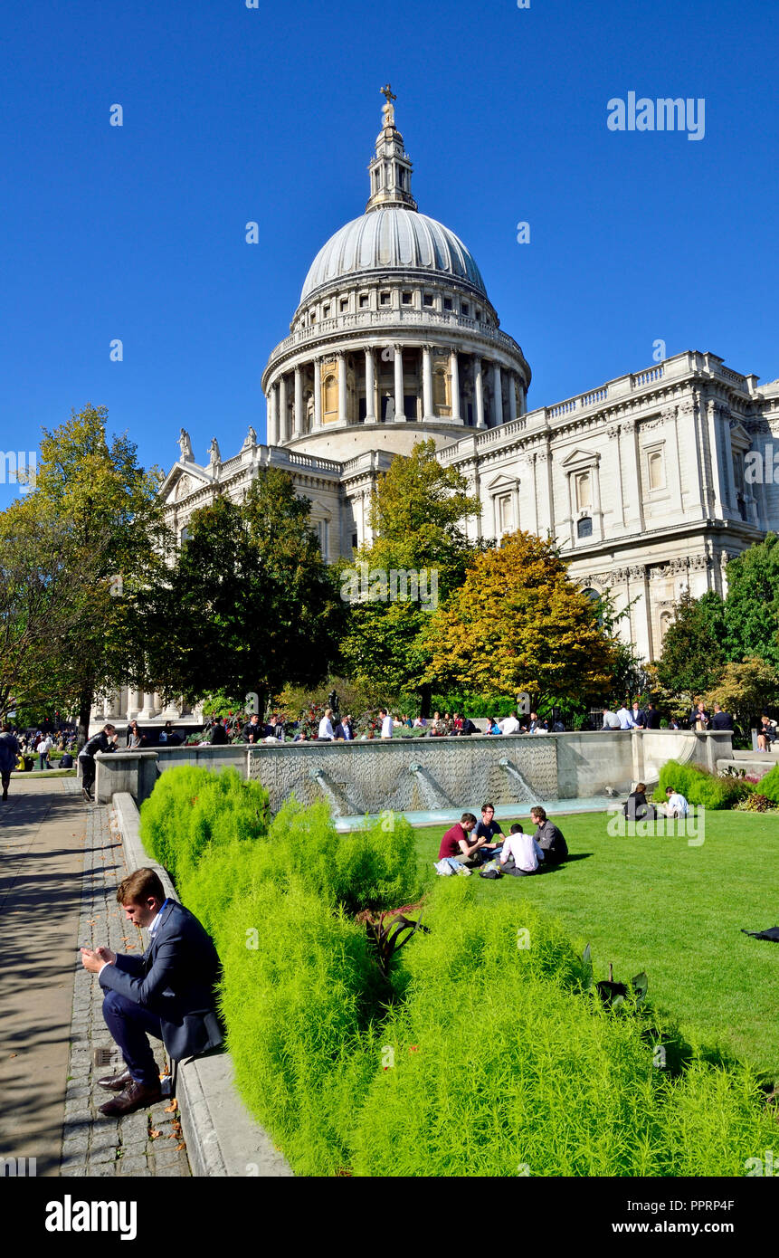 People relaxing at lunchime by St Paul's Cathedral, London, England, UK. Man on his mobile phone Stock Photo