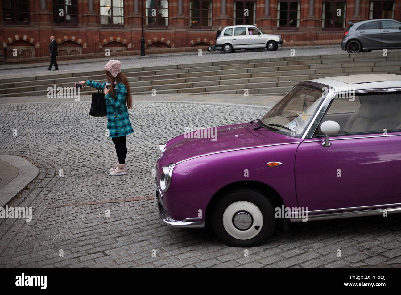 Girl taking a selfie in front of a Nissan Figaro. Stock Photo