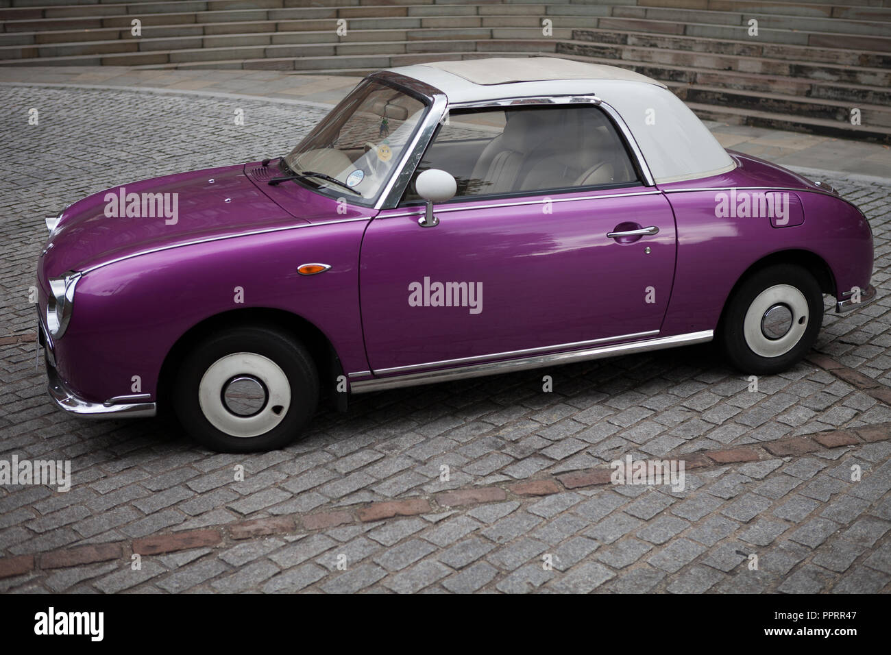 Purple Nissan Figaro parked on cobblestones. Stock Photo