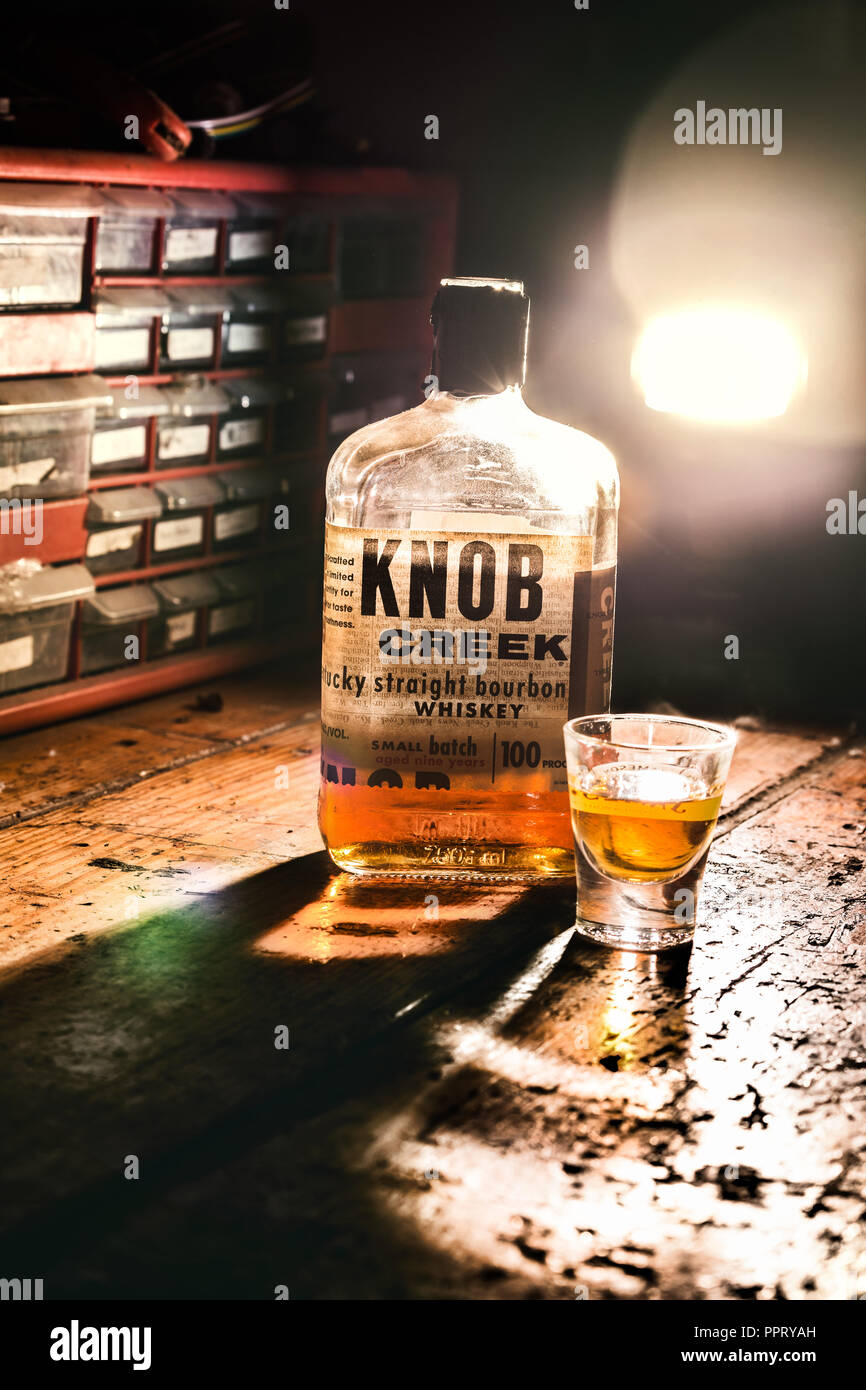 A bottle of Knob Creek sits on a work bench in a shop.  It's probably not just being hit afterhours... Stock Photo