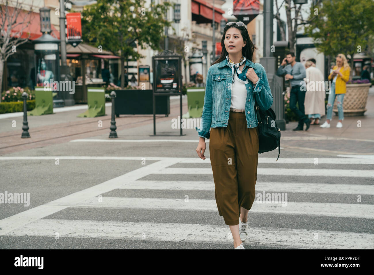 elegant woman crossing road, she looks relax because today is her holiday, she is going shopping Stock Photo