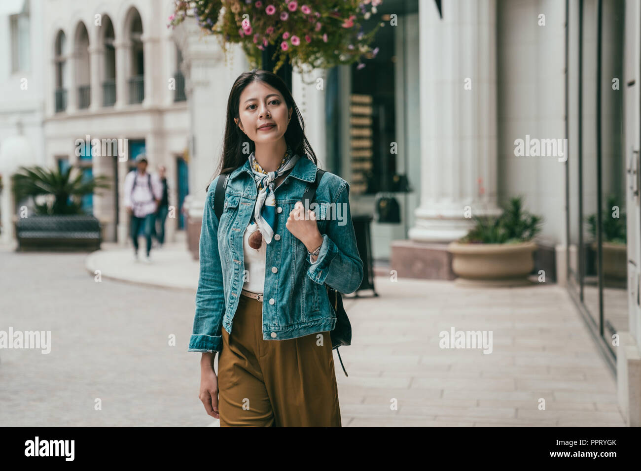 young female traveler smiling walking on the street with eyes full of curious feeling Stock Photo