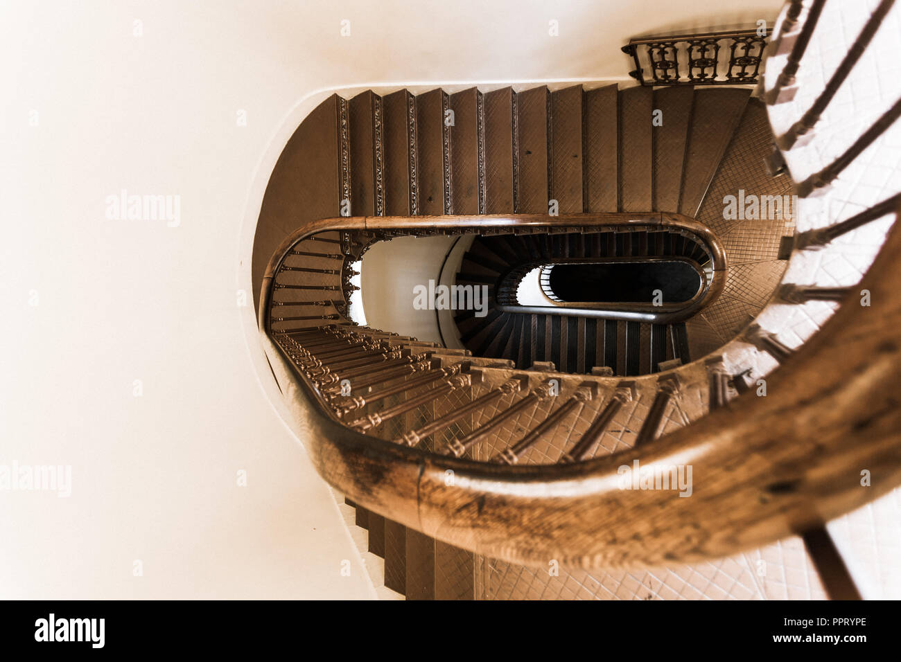 Oval shaped spiral vintage staircase with wrought iron and wooden railing Stock Photo