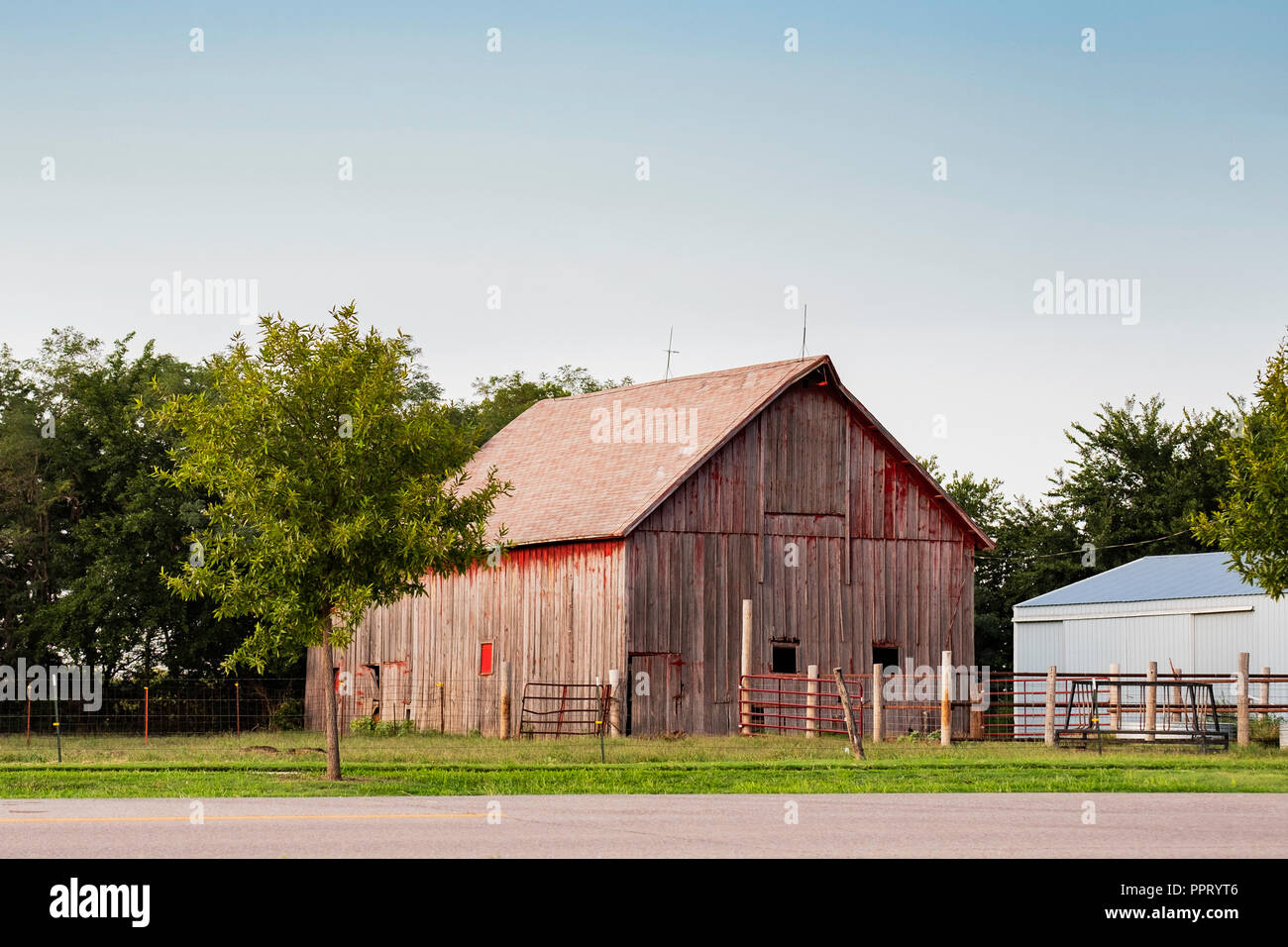Old faded red wooden barn  beside a road in the countryside outside of Wichita, Kansas, USA. Stock Photo