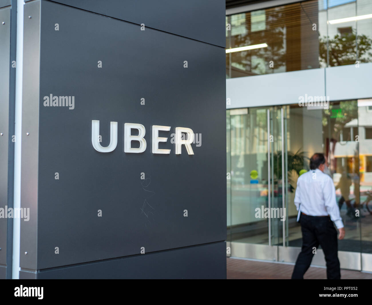 Uber headquarters office entrance sign with man walking inside Stock