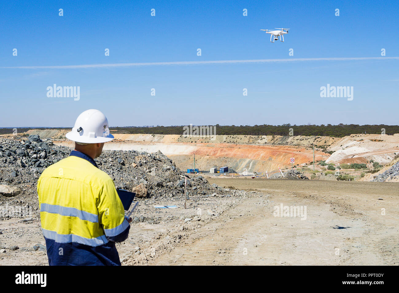 Surveyor using a drone to measure ore stockpile at a gold mine in Western Australia Stock Photo