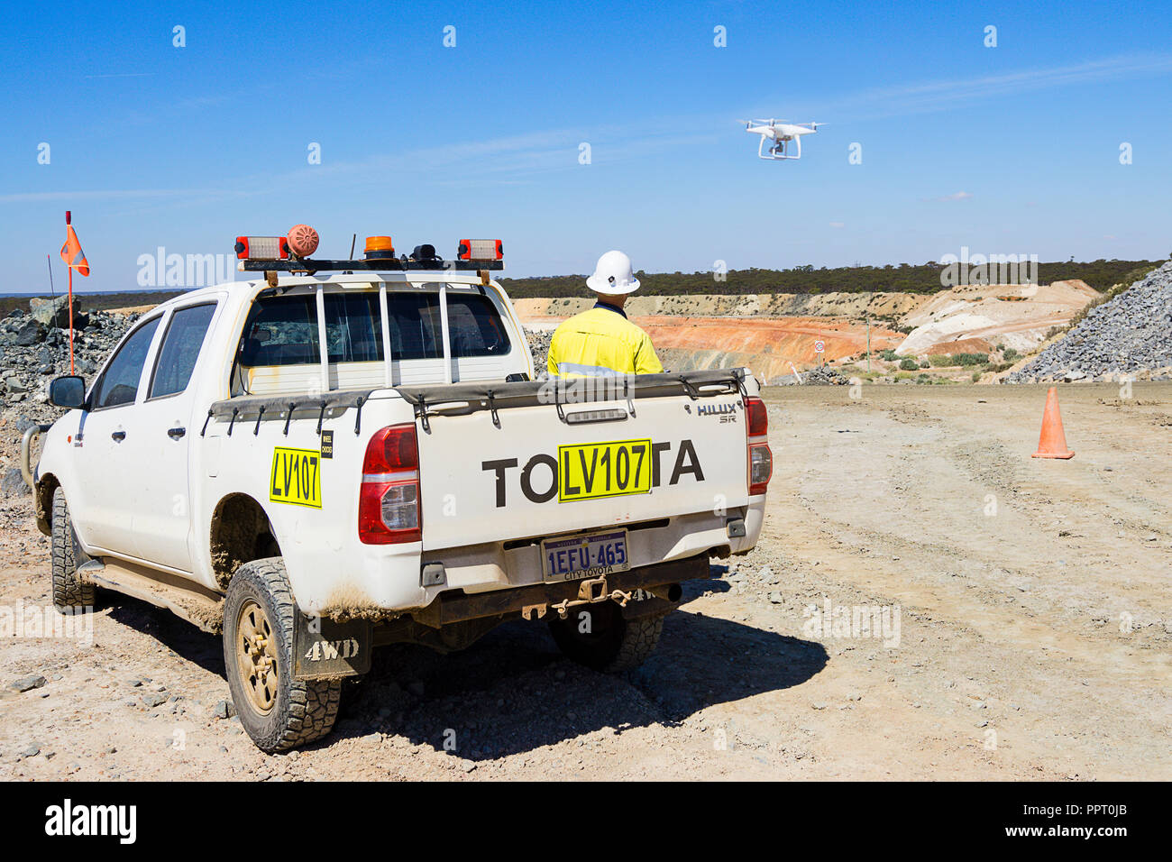 Surveyor using a drone to measure ore stockpile at a gold mine in Western Australia Stock Photo
