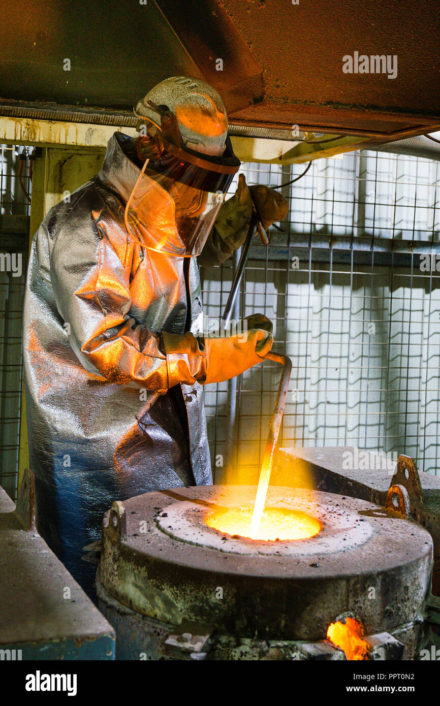 Worker in protective clothing pouring gold from a furnace at a gold mine in Western Australia Stock Photo