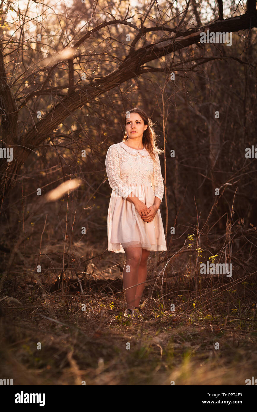 Beautiful girl standing in a field on a sunset background Stock Photo ...
