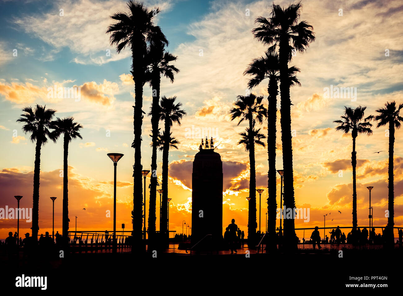 Adelaide, Australia - October 7, 2017: Walking people and Pioneer Memorial silhouettes at Moseley Square on Glenelg during sunset. Stock Photo