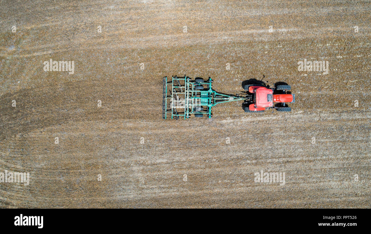 A tractor dragging a tiller navigates the fields of a farm near Newburg