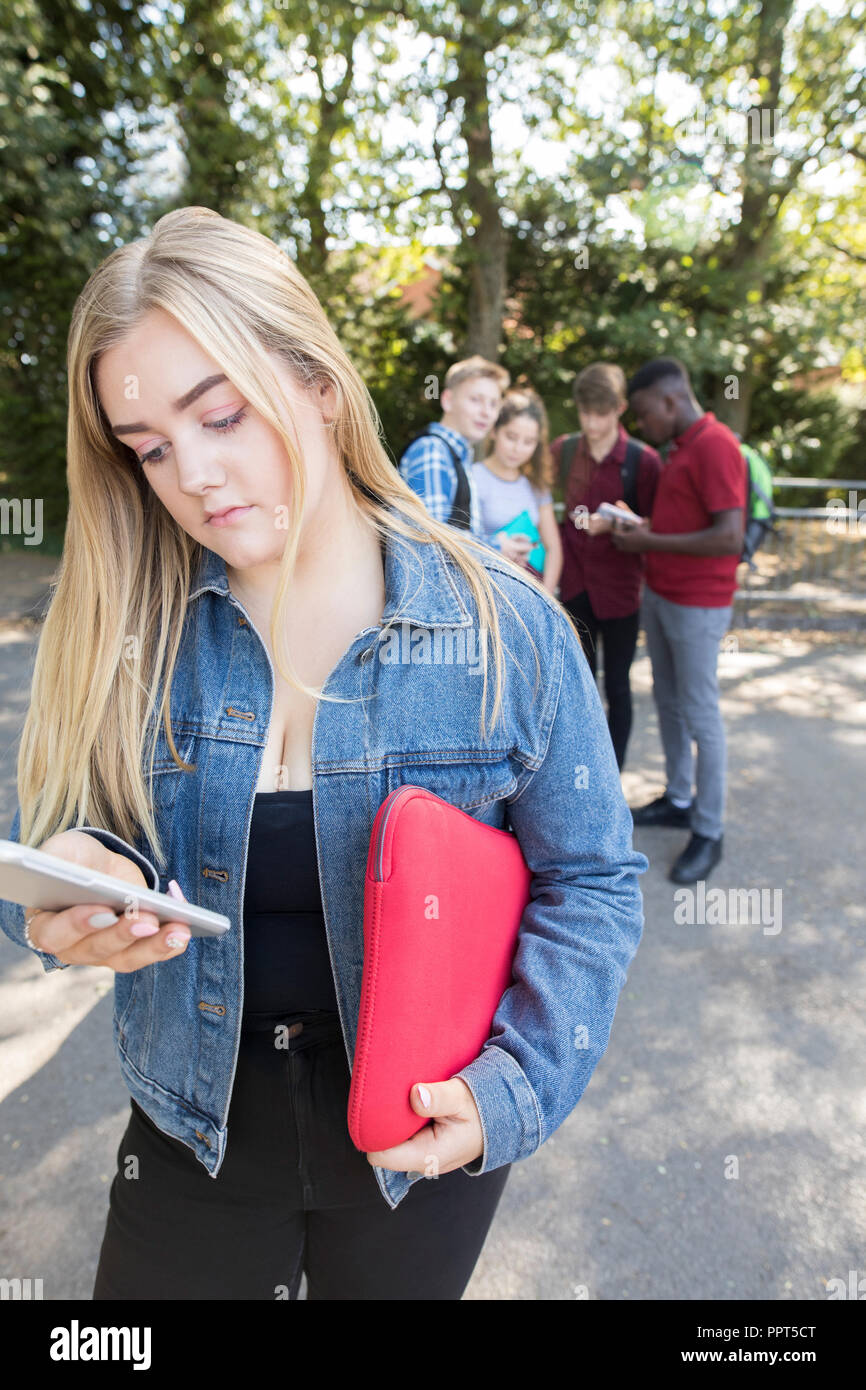 Unhappy Teenage Girl Being Bullied By Text Message At School Stock Photo