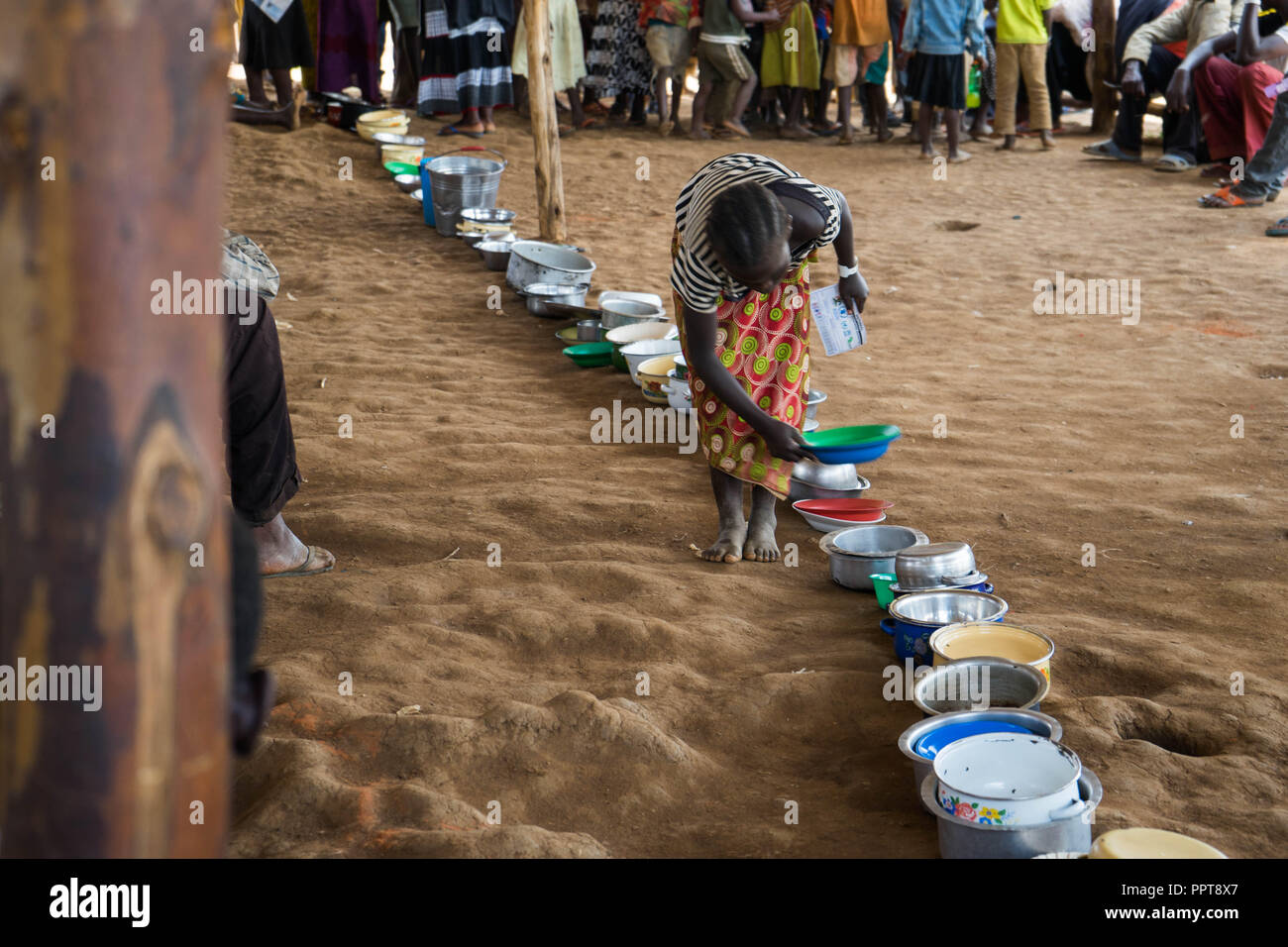 A Congolese female child refugee seen seen leaving her plate to line up for food distribution in Kyangwali refugee settlement. Stock Photo