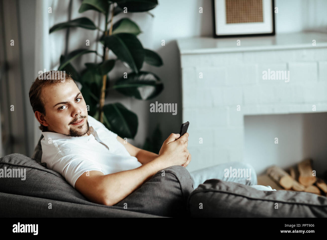 Handsome man is sitting on the sofa at home Stock Photo