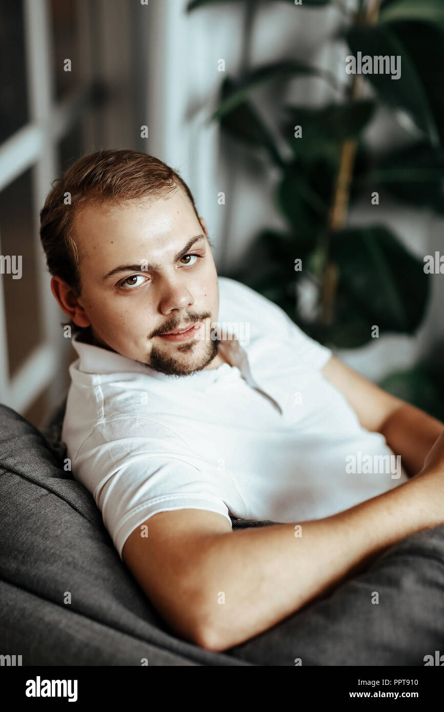 Handsome man is sitting on the sofa at home Stock Photo