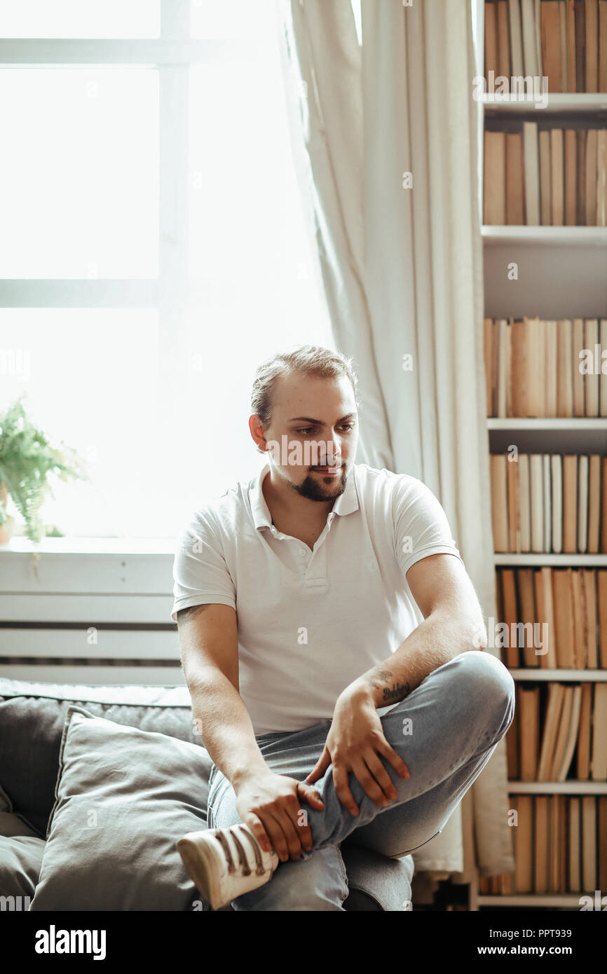 Handsome man is sitting on the sofa at home Stock Photo