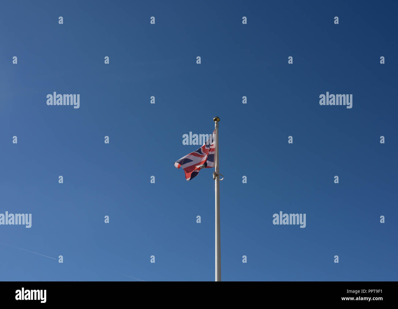 Union jack flag fluttering in the wind in a clear blue sky in bury ...
