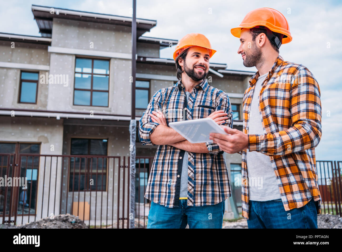 happy architects using digital tablet at construction site Stock Photo