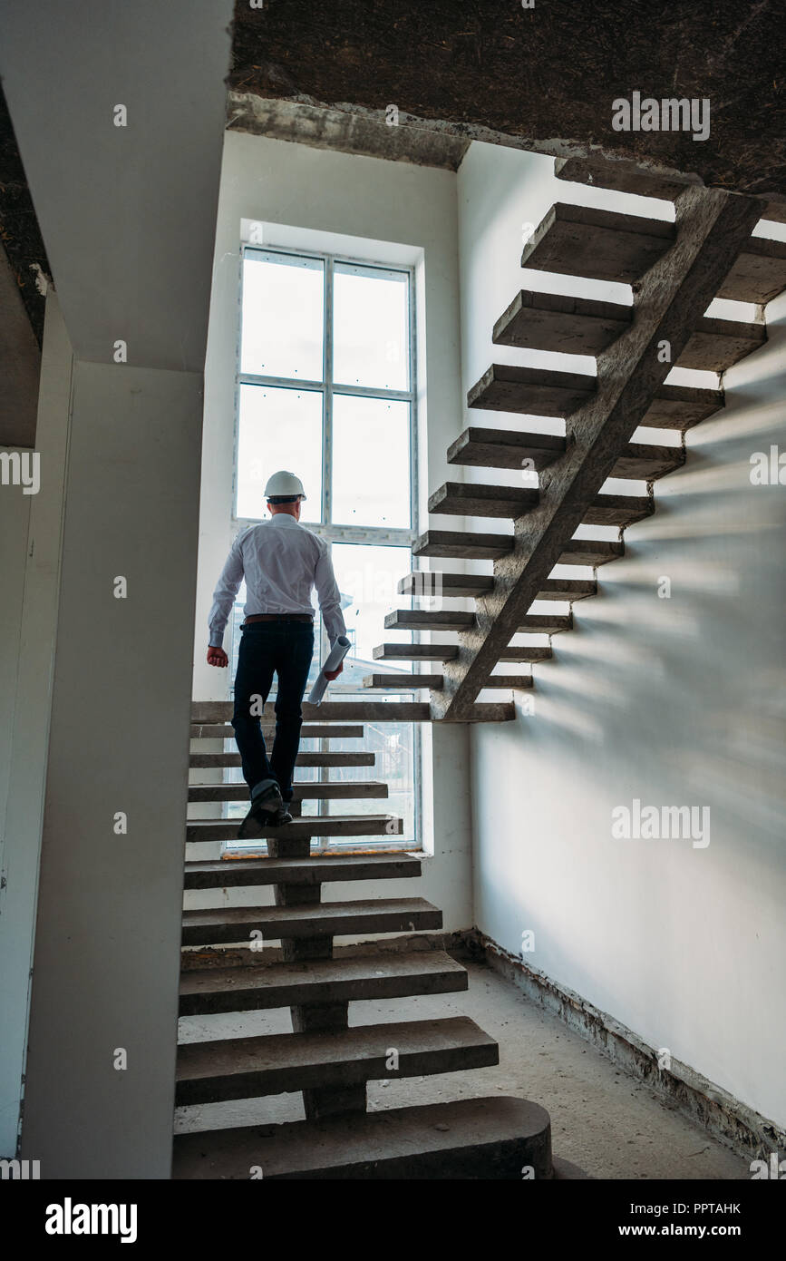 rear view of architect going upstairs inside of building house Stock