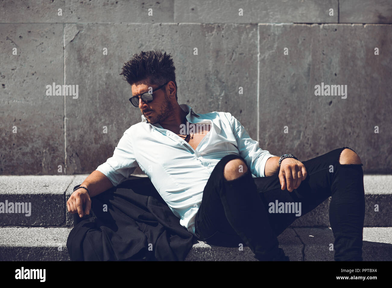 Portrait of a successful young businessman dressed in suit walking down the stairs . Concept Fashionable Young Man Stock Photo