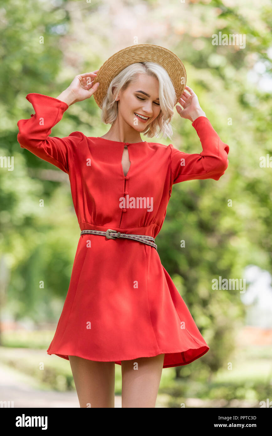 stylish attractive girl in red dress and straw hat posing in park Stock ...