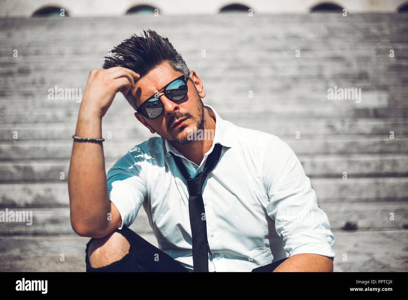 Depressed unsuccessful businessman feels terrible headache, hands shocked by bankruptcy stock downfall sitting on stone stairs. Stressed tired man fee Stock Photo