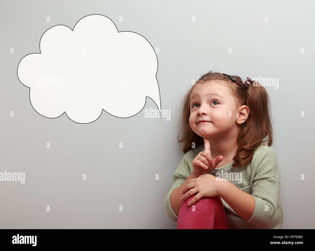 Fun thinking kid looking up on idea cloud bubble with empty copy space on blue background Stock Photo