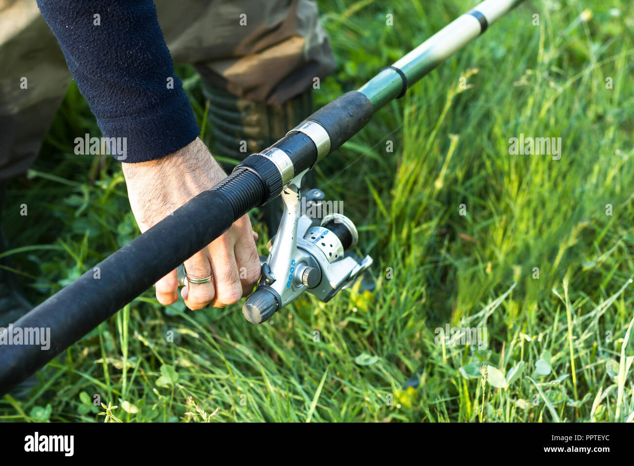 Ground fishing. The angler's hand adjusts the tension of the fishing line with the reel. Stock Photo