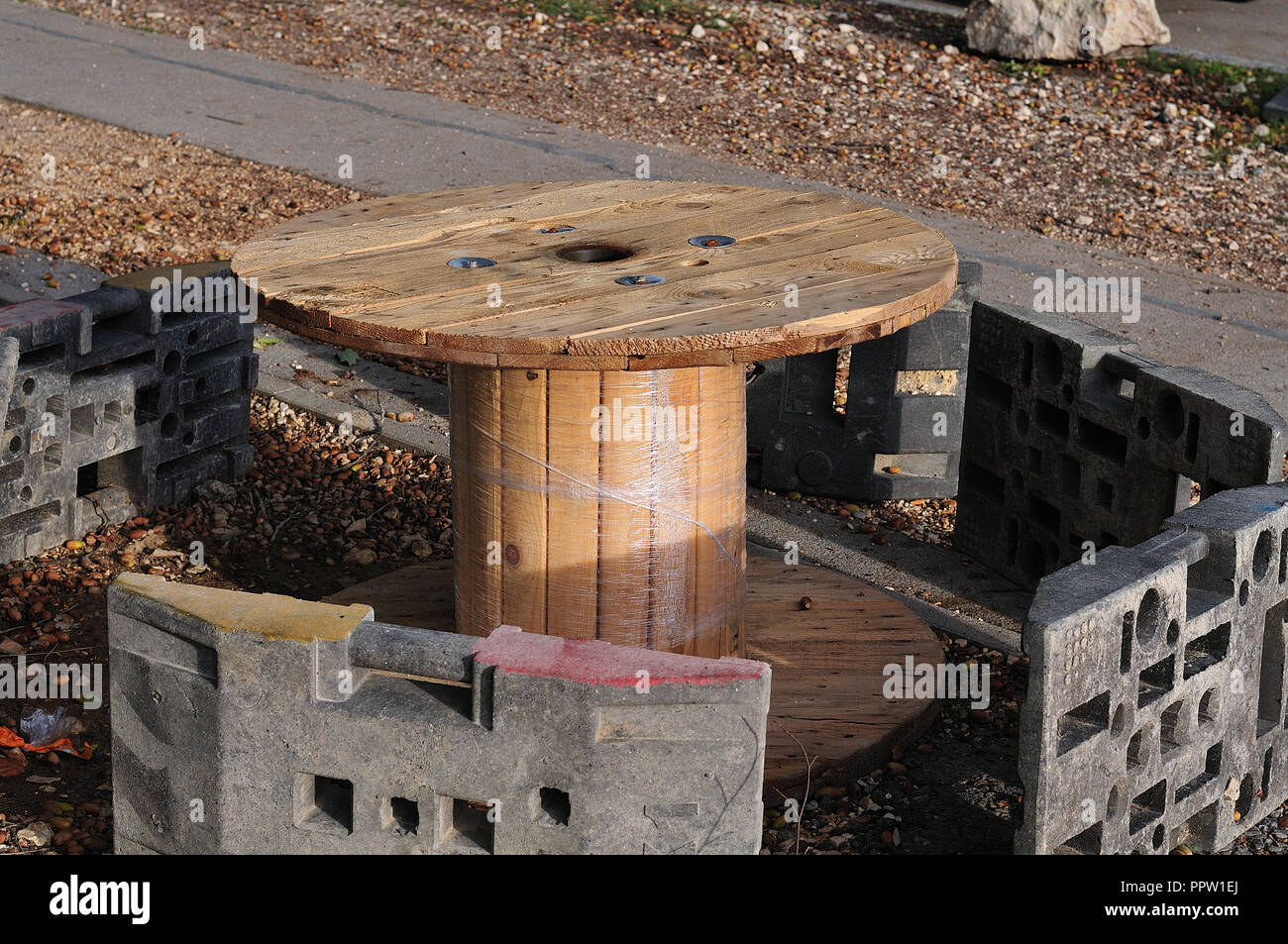 resting place beside construction site, improvised with empty wooden cable spool and  kiln furniture of temporary fencing Stock Photo