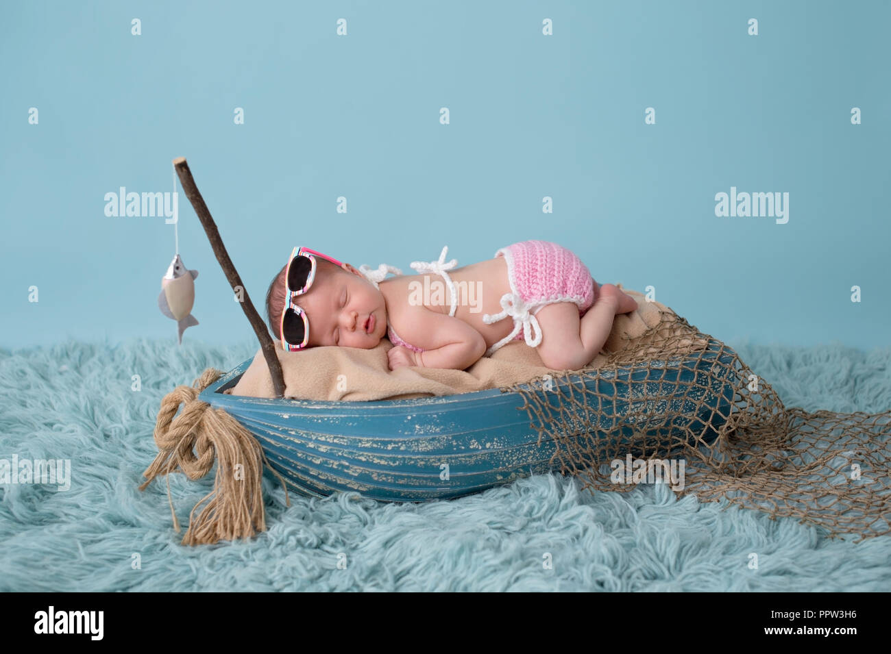 https://c8.alamy.com/comp/PPW3H6/portrait-of-a-nine-day-old-newborn-baby-girl-she-is-sleeping-in-a-miniature-fishing-boat-and-wearing-sunglasses-and-a-pink-bikini-shot-in-the-studio-PPW3H6.jpg