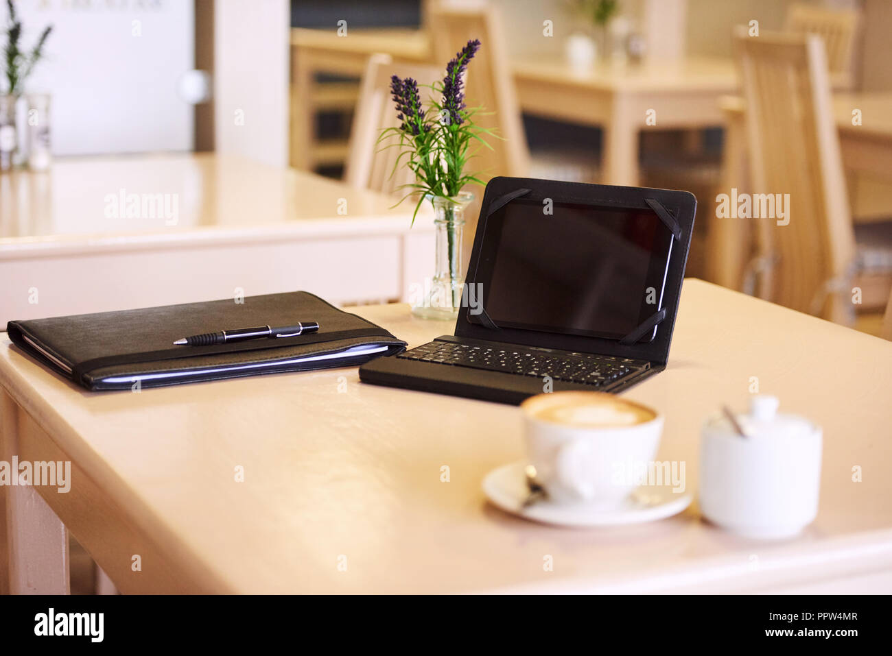 electronic tablet and keyboard set up on table with a notepad and some coffee as well as a lavender center piece on a bright summer morning. Stock Photo