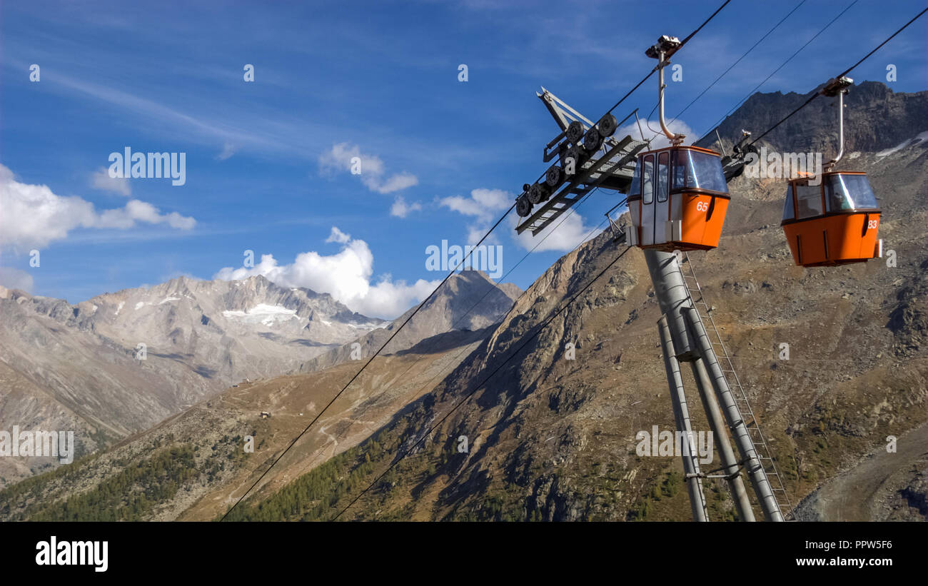 Two small red cable car cabins against the backdrop of the gorgeous mountains near the village of Saas-Fee, the main village in the Saastal Stock Photo