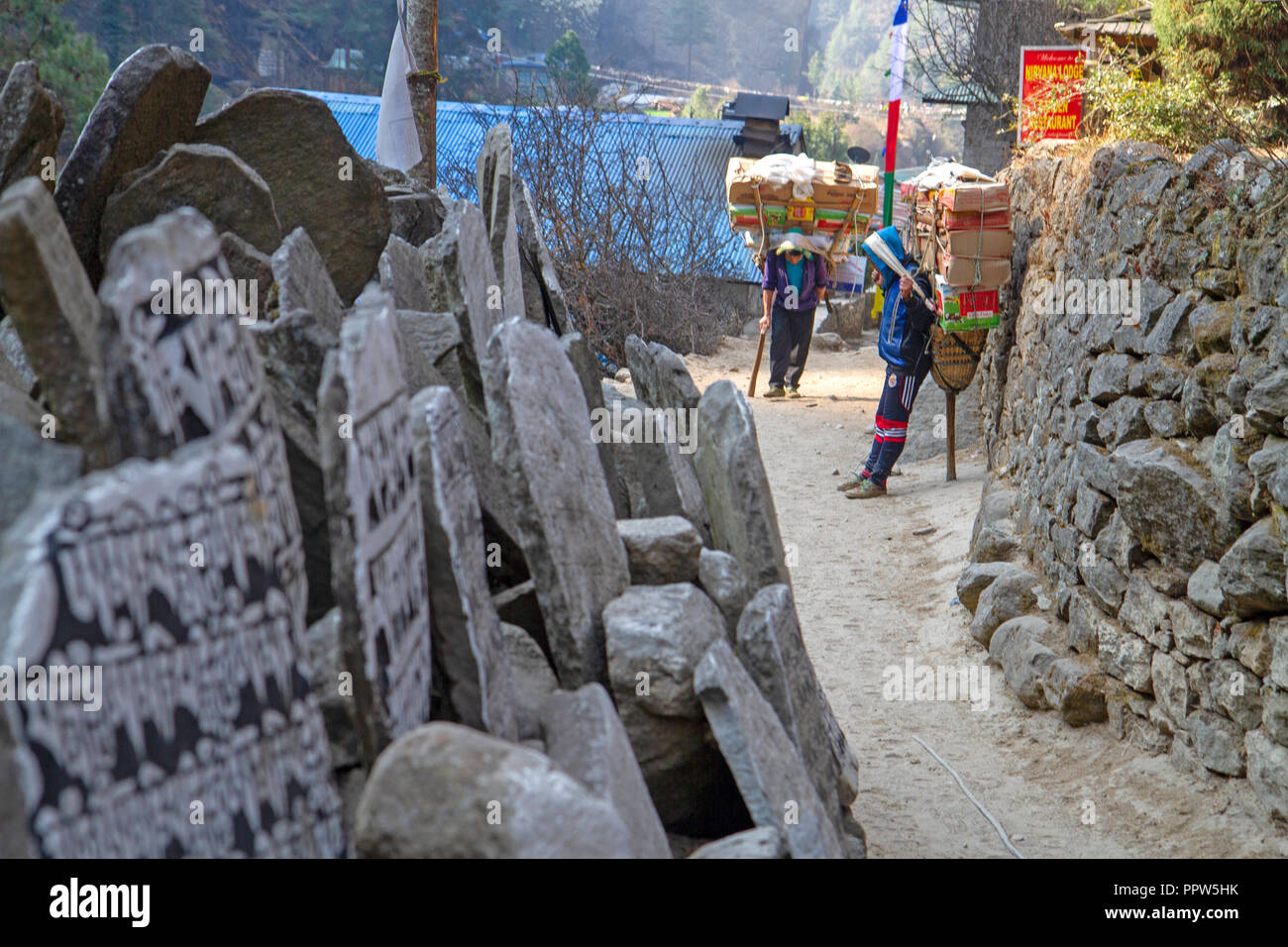 Mani stones and porters on the trail to Everest Base Camp Stock Photo