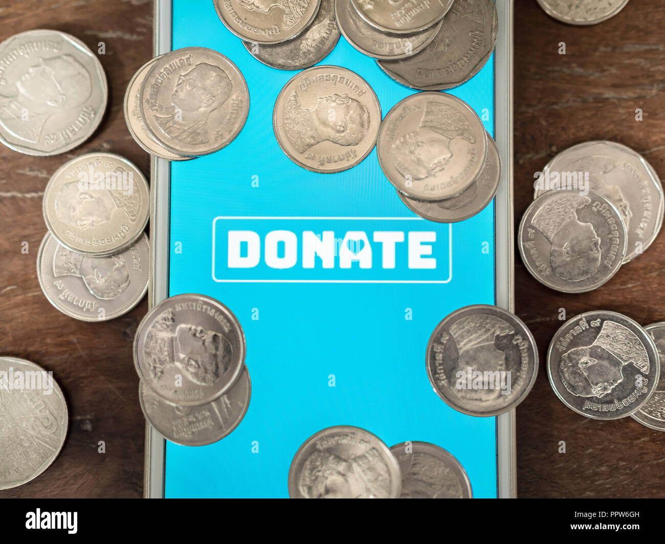 Flat lay donate icon button on blue screen on white mobile phone with ...