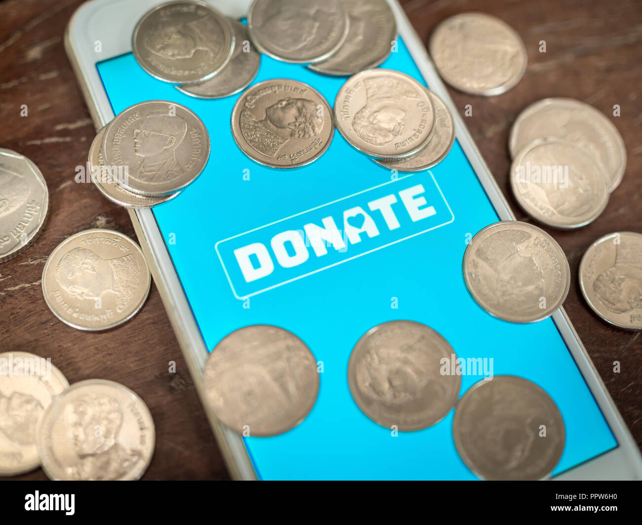 Close-up donate icon button on blue screen on white mobile phone with ...