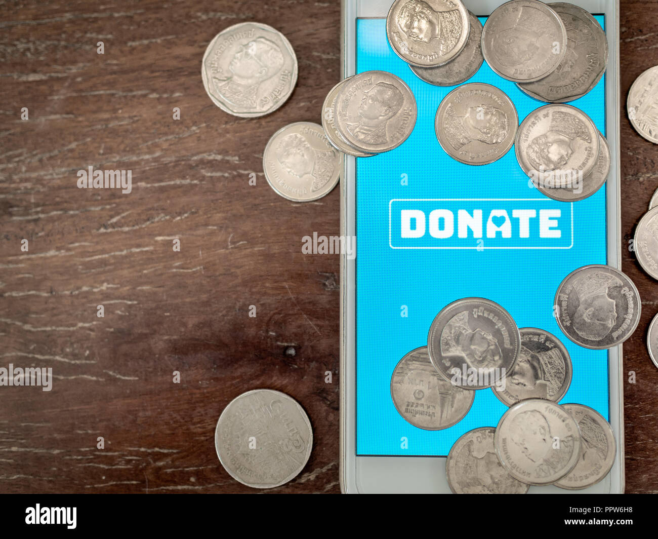 Flat lay donate icon button on blue screen on white mobile phone with ...