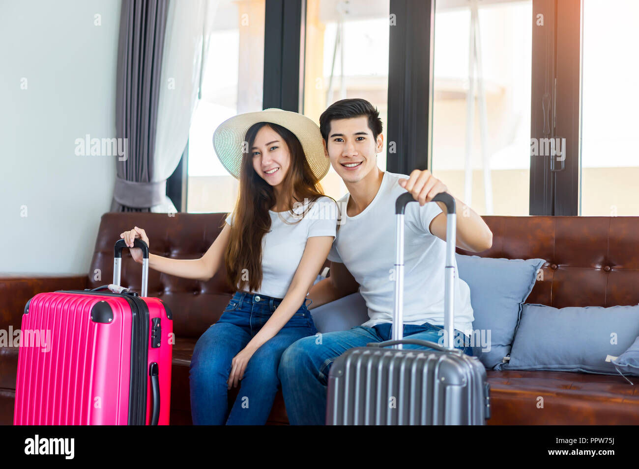 Happiness Asian couple traveler packing suitcases preparing for travel vacation together.Happy enjoy to smiling at home in the living room. Stock Photo