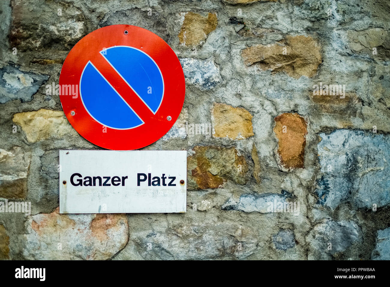 Against a brick wall in the Swiss city of Lucerne a red and blue sign is indicating that no parking is allowed on this square. Stock Photo