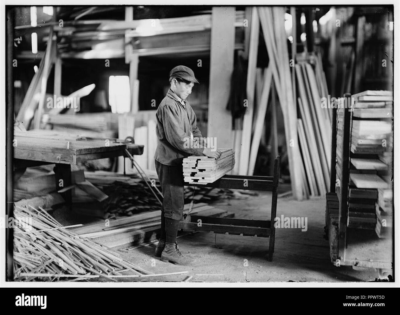 Boy probably about 13 years old, tying strips which he has taken away from the planer. Schultze Waltum Co., Planing Mill. Stock Photo